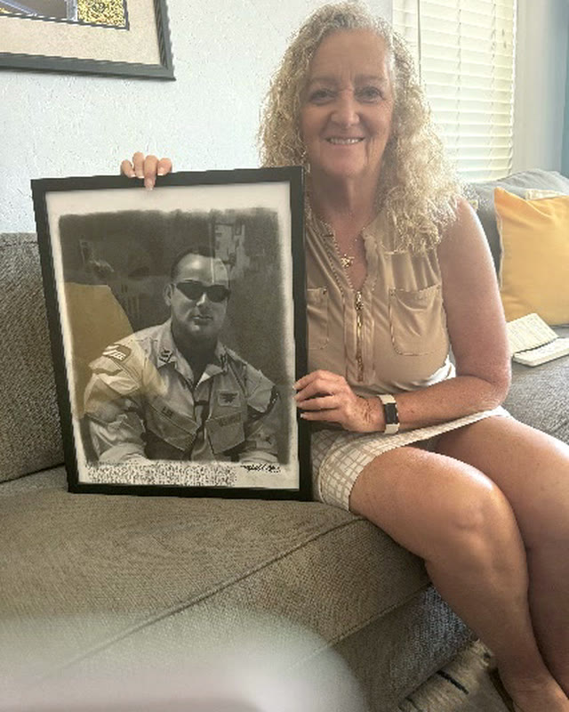 Debbie Lee, known as Mama Lee, holding a portrait of her son Marc.